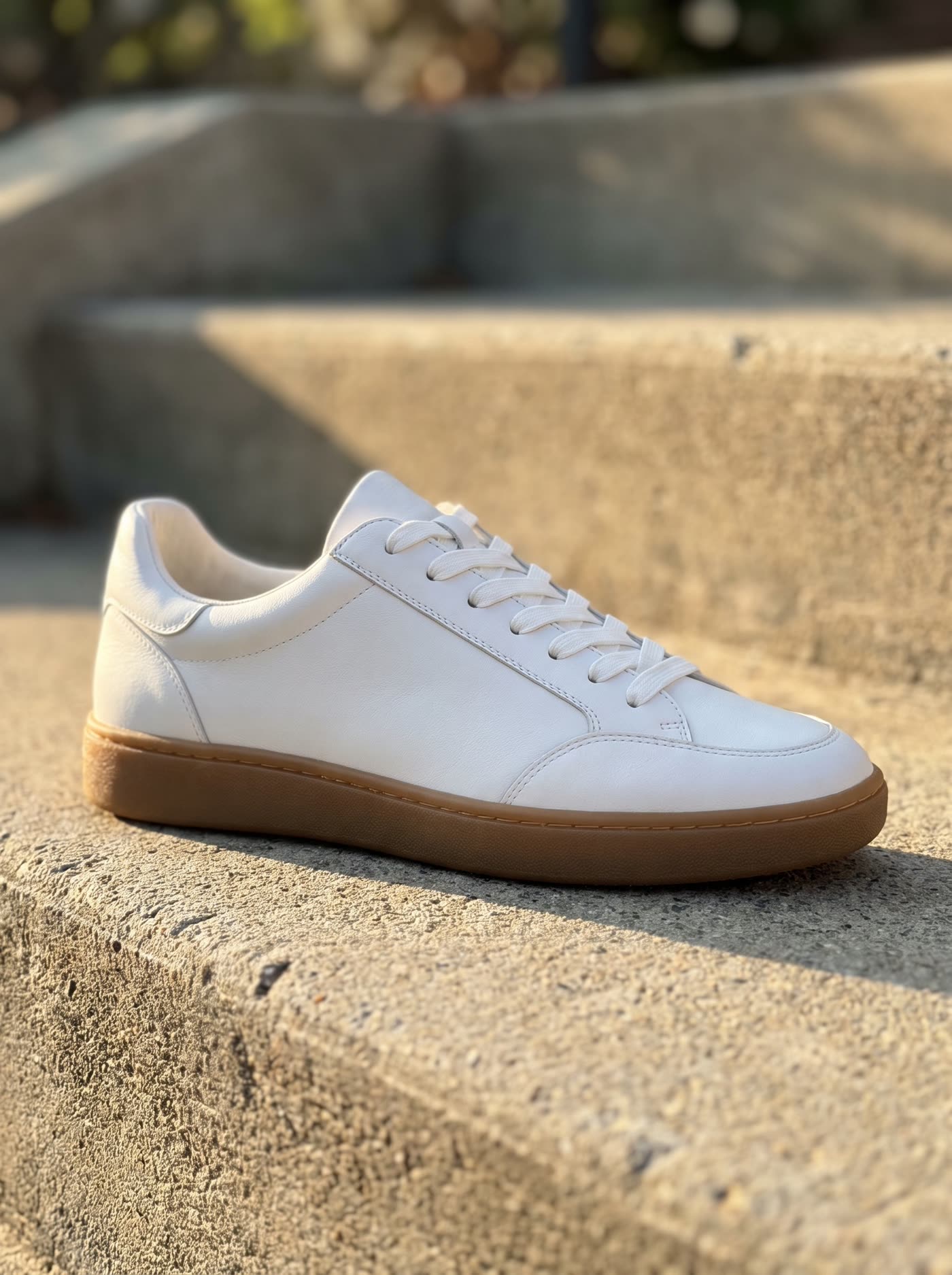 The white sneaker on a sunlit concrete step in morning light, background softly out of focus