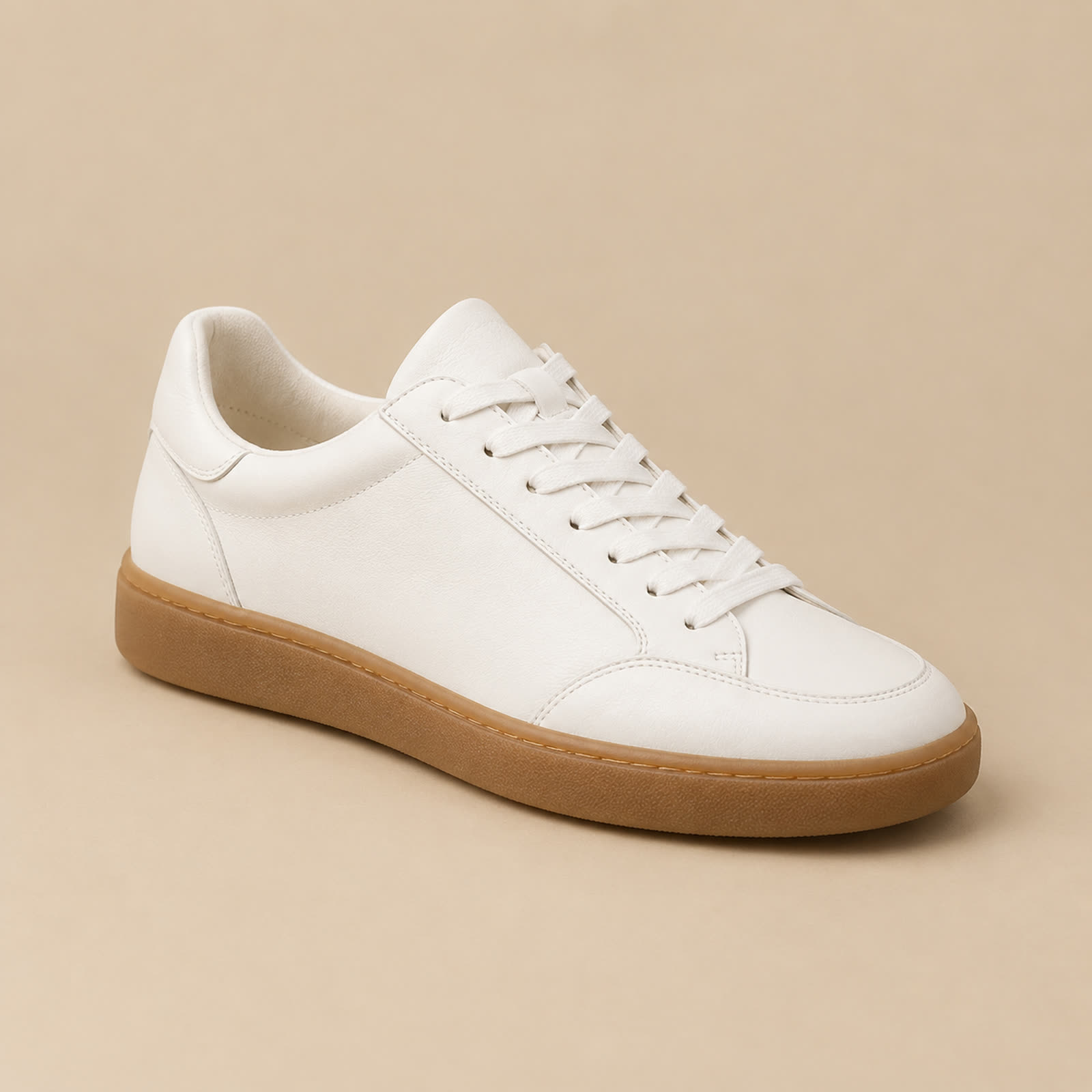The reference photo: a plain white low-top sneaker with a gum sole on a warm beige studio backdrop